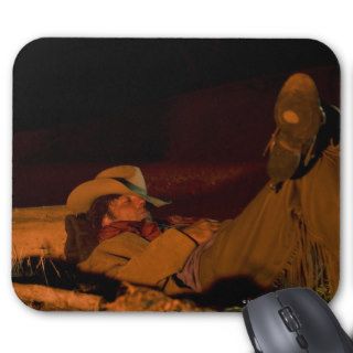 A cowboy sleeping next to a campfire mouse pads