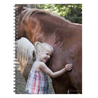 Caucasian girl petting horse in corral note books